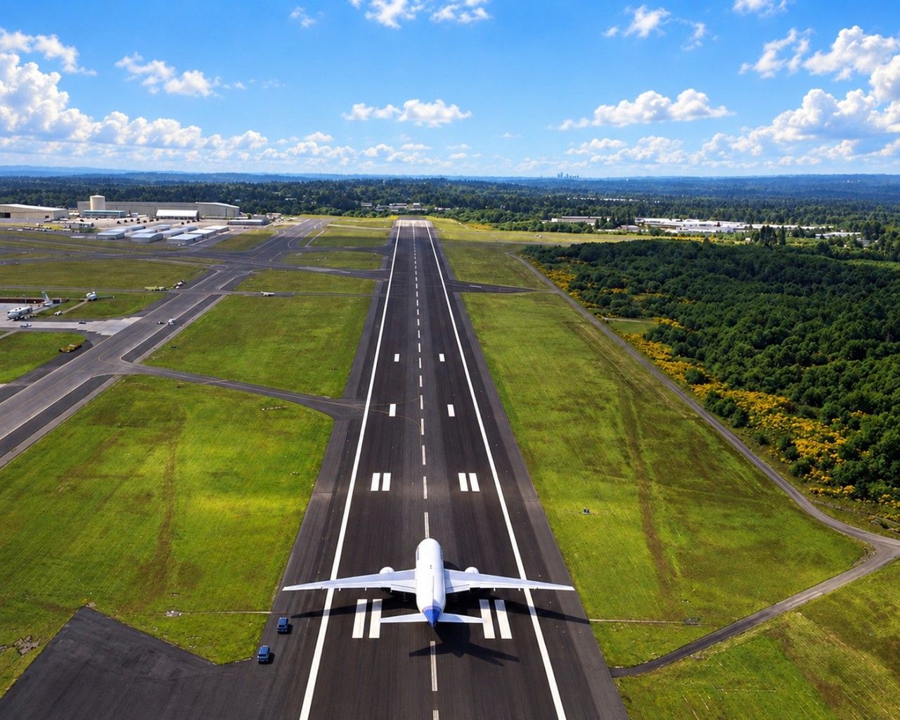 An airplane on a runway with a clear sky and distant buildings.