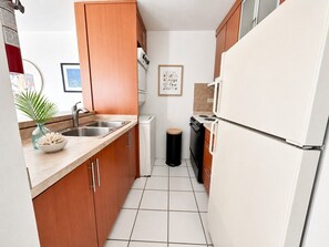 Eine kleine Küche mit Holzschränken, einem weißen Kühlschrank, einer Spüle und einem Herd.