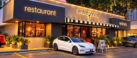 Un restaurante con un automóvil estacionado frente a él, un cartel y un edificio de diseño moderno.