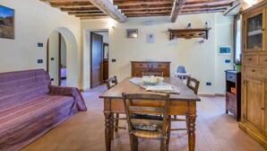 A dining area with a wooden table and chairs, a sofa, and a wooden cabinet. - Nice apartment in villa for 6 people with pool, WIFI, TV and terrace (Pescia)