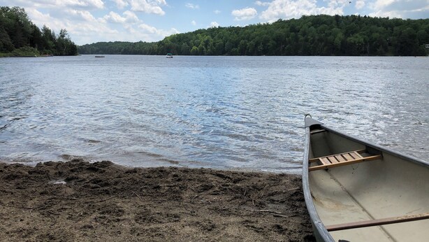 Un lago tranquilo con un bote de madera en la orilla.