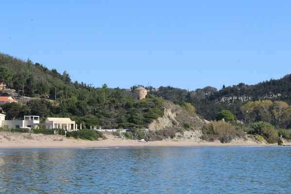 A coastal area with a beach, a tower, and buildings on a hillside.