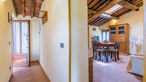 A hallway with a wooden ceiling, a dining area with a table and chairs, and a kitchen area with a refrigerator. - Lovely apartment in villa for 3 guests with WIFI, pool, TV and terrace (Pescia)
