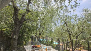 Ein Essbereich im Freien mit einem Tisch für zwei Personen, umgeben von Bäumen und Blick auf einen Pool.