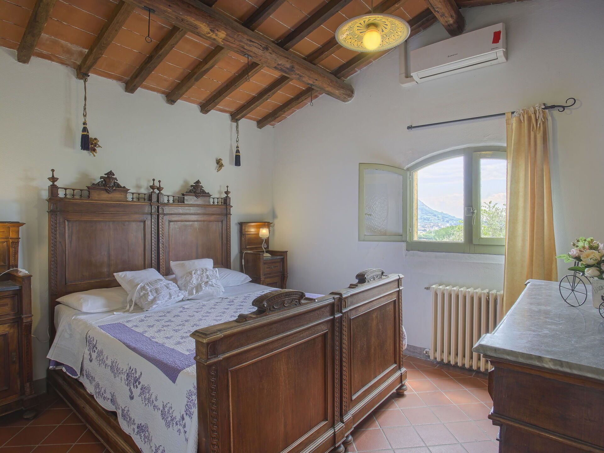 Un dormitorio tradicional con una cama de madera, una mesita de noche, un tocador y una ventana con vistas.