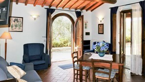 A cozy living room with a sofa, a dining table with chairs, and a wooden ceiling. - Cosy apartment for 4 people with WIFI, pool, TV, terrace and pets allowed (Bucine)