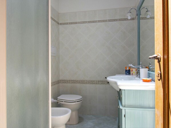 Une salle de bain avec des toilettes, un lavabo et une douche.