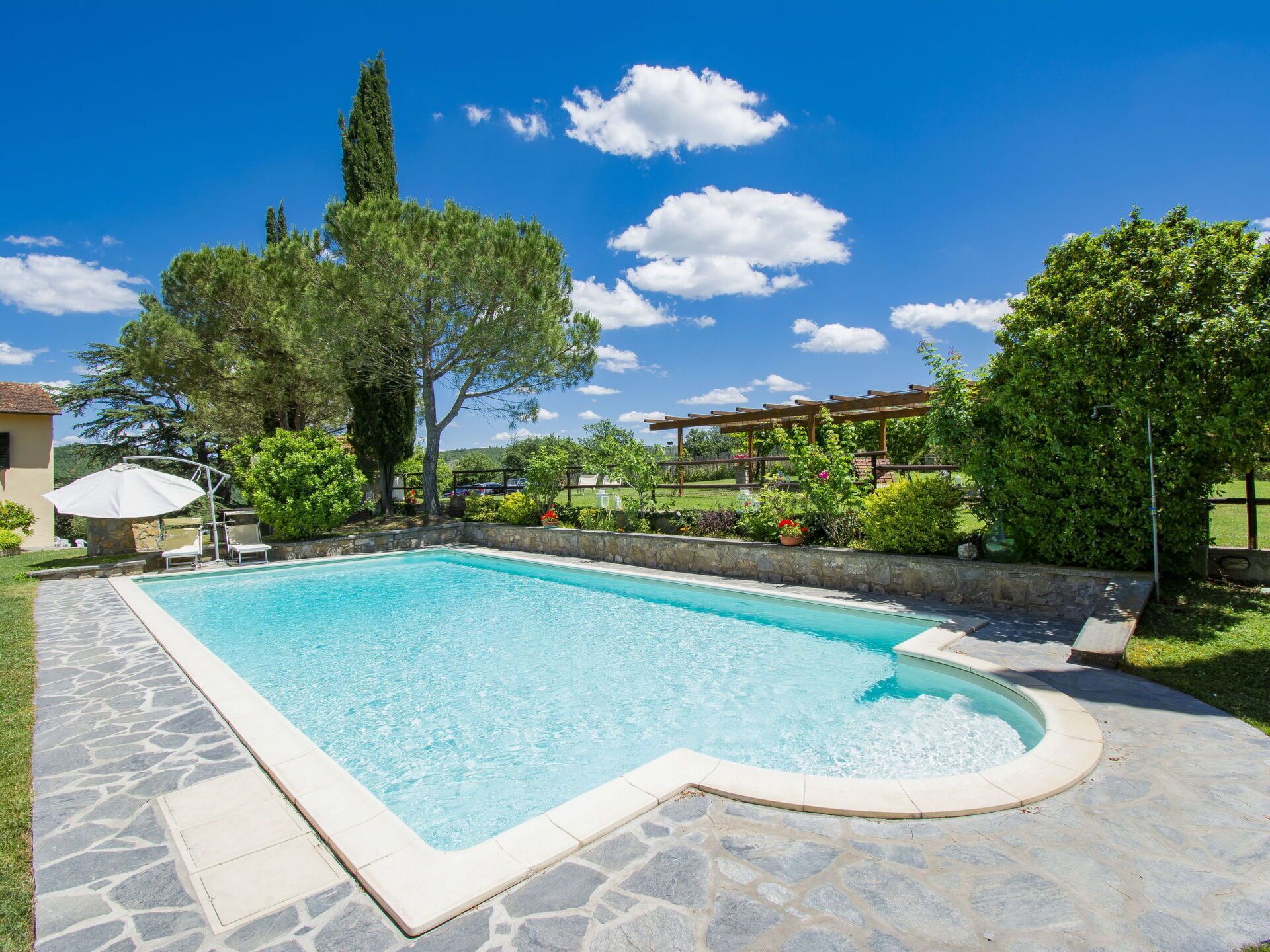 Une piscine rectangulaire bordée de pierres, entourée d’une terrasse également en pierre.