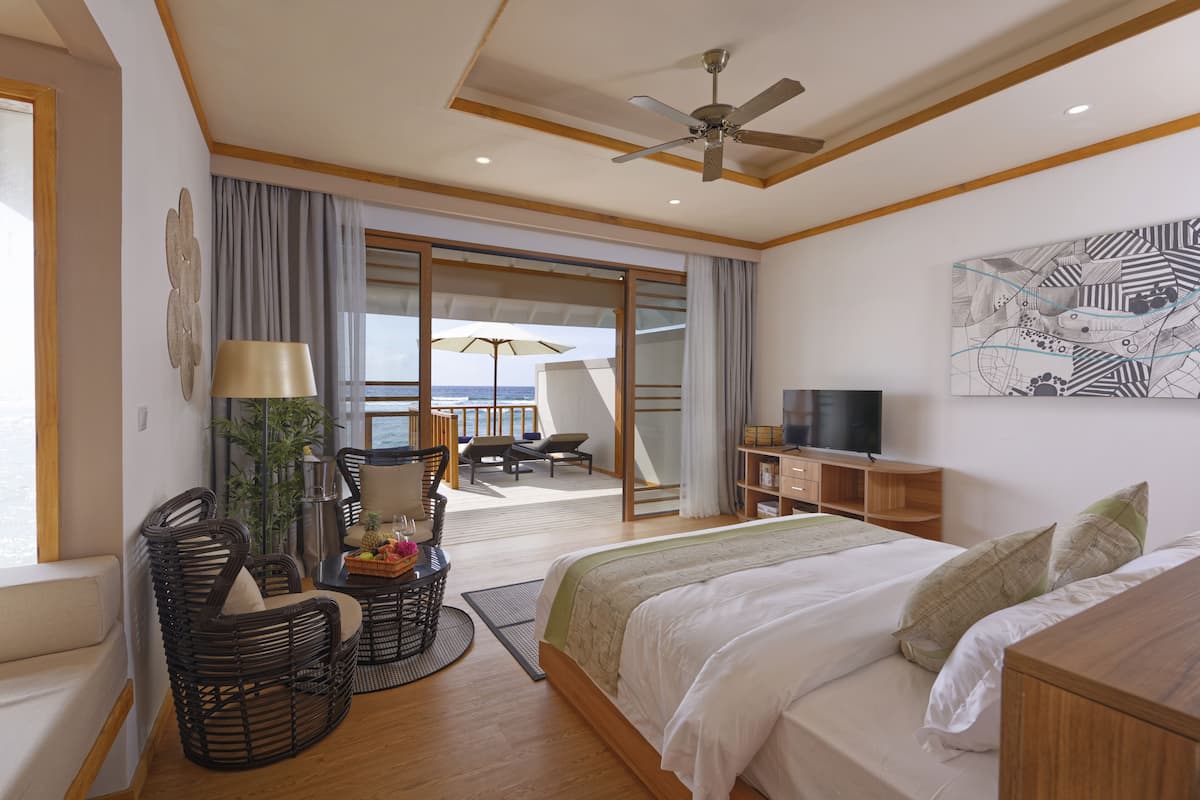A spacious bedroom with a large bed, a television, and a balcony with a view of the sea.