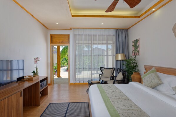 A hotel room with a bed, a TV, a desk, a chair, a lamp, and a view of the outdoors.