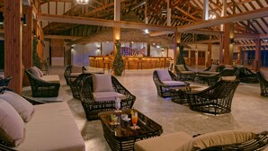 A spacious indoor area with wicker furniture, a bar area, and a thatched roof structure.