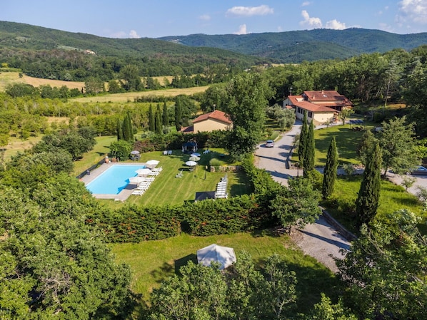 Vue aérienne d’une propriété dotée d’une piscine, de chaises longues et d’une pelouse bien entretenue.