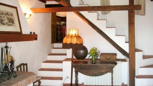 Un escalier avec des marches en bois et un mur blanc. On y trouve une table avec un vase de fleurs et une lampe.