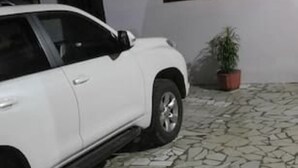 A white car parked in a courtyard with a tiled floor and a potted plant. - Nzecy Appart. A studio with a velvety, air-conditioned living room. (Libreville)