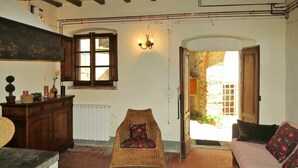 A cozy room with a wicker chair, a sofa, a wooden cabinet, and a window with a view of an outdoor brick wall. - Cosy apartment in villa for 6 people with WIFI, pool, TV and terrace (Casa Biondo)