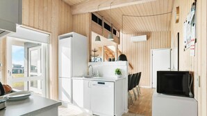A modern kitchen with white appliances, a small island, and a dining area with chairs. - Pet friendly home in Faaborg with sauna (Faaborg)