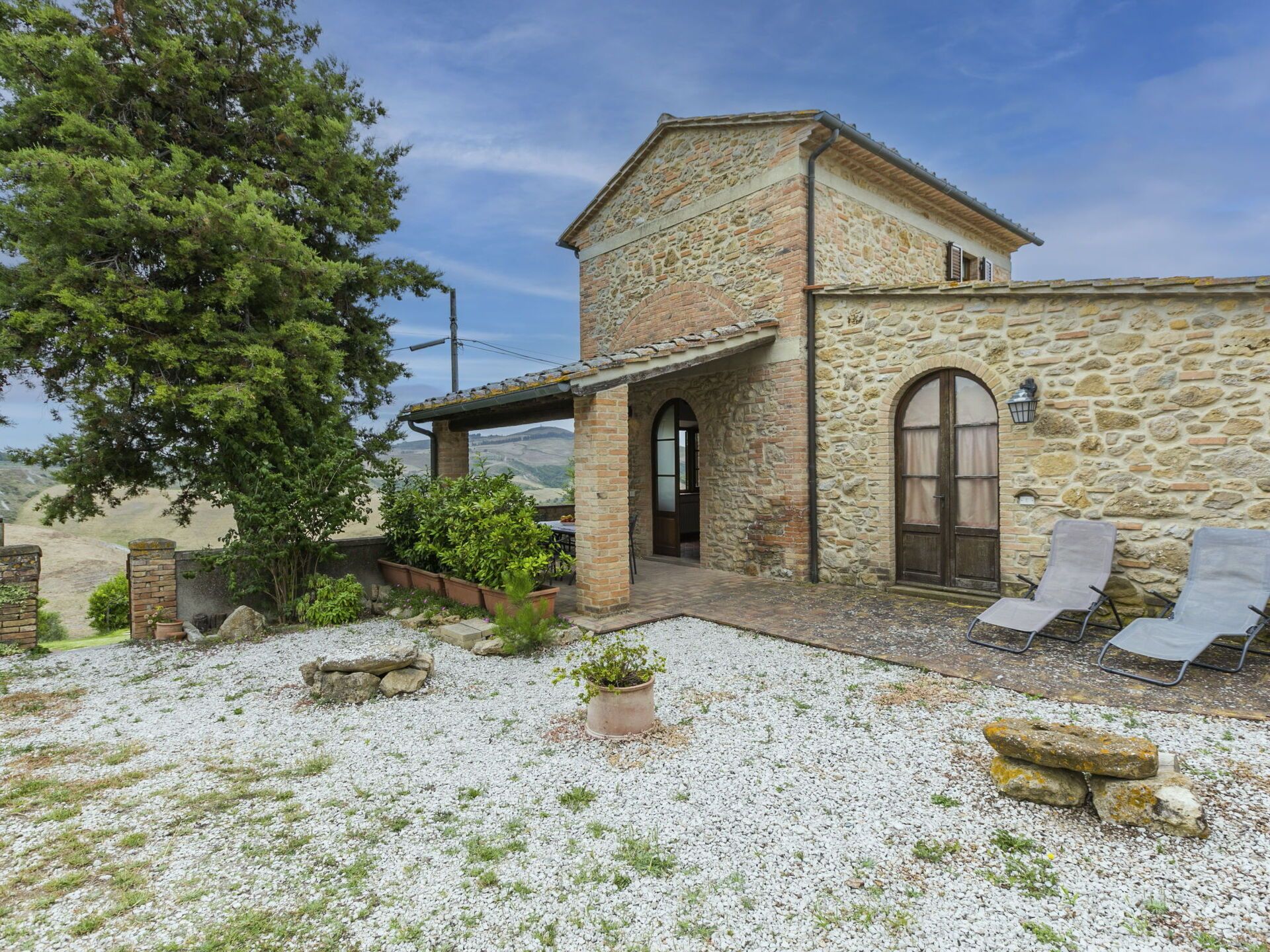 Un edificio in pietra con patio coperto, posti a sedere all'aperto e vista sulle colline.