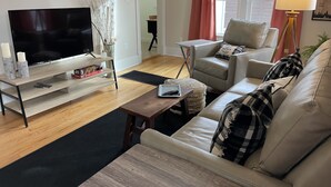 Un salon comprenant un téléviseur, un canapé, un fauteuil, une table basse et une lampe.