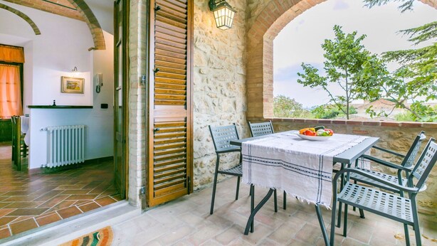 Un patio con mesa y sillas, un muro de piedra y vistas a zonas verdes.