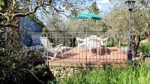 A fenced patio area with outdoor furniture, a green umbrella, and a lamp post.