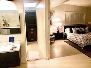 A bedroom with a bed, bedside table, lamp, and a dresser with a mirror. - Waterfront beautifully renovated 6 Bedrooms 4 Bath , Gated Private Home (Islamorada)