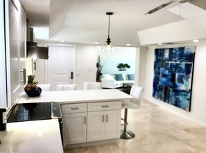 Une cuisine moderne dotée d’un îlot central, de meubles blancs et d’un ventilateur de plafond.