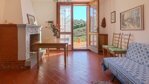 Un'accogliente stanza con camino, un tavolo da pranzo, una poltrona e un'ampia finestra con vista sul paesaggio.