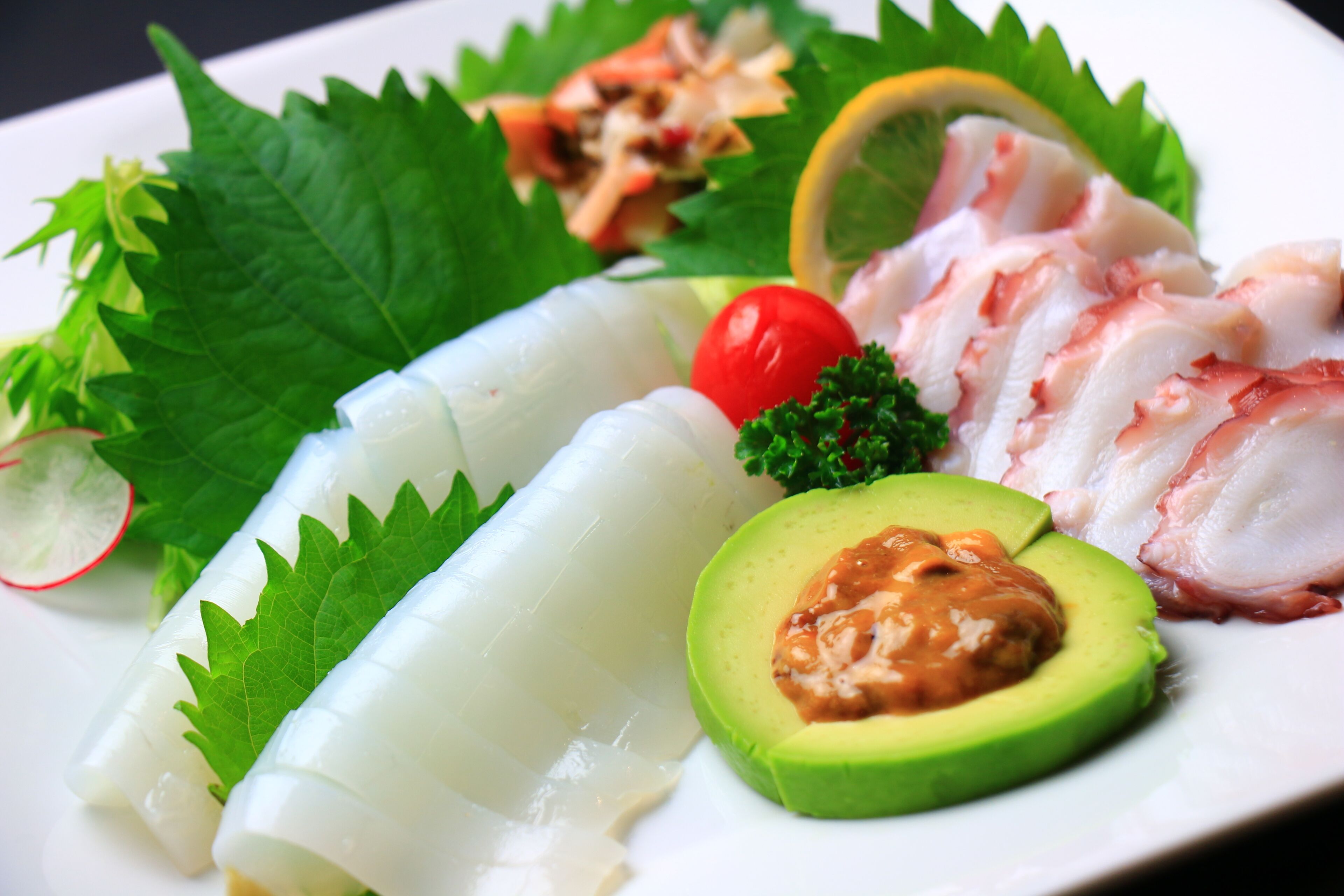 A plate with various food items including avocado, fish, and vegetables.