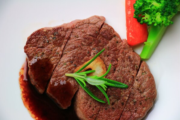 A steak with rosemary garnish and vegetables on a plate.