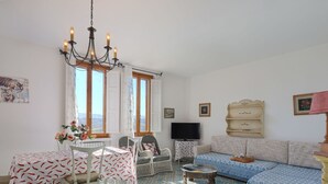 A living room with a dining area, a sofa, a TV, and a chandelier. - Beautiful apartment for 6 people with pool, WIFI, TV, patio, pets allowed and panoramic view (Certaldo)