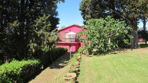 A pink building surrounded by trees and a grassy area with potted plants. - Beautiful apartment for 6 people with pool, WIFI, TV, patio, pets allowed and panoramic view (Certaldo)