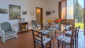 Zona pranzo con tavolo in vetro, sedie in vimini e lampadario.