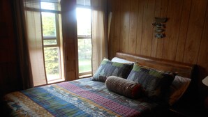 A bedroom with a wooden headboard, a quilted bedspread, and two pillows.