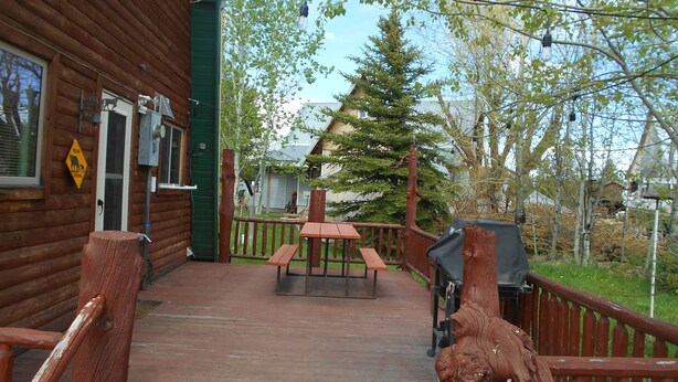 A wooden cabin with a deck, picnic table, and a bear crossing sign.