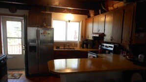 A kitchen with wooden cabinets, a refrigerator, a stove, and a sink.