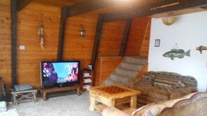 A cozy cabin interior with a wooden interior, a television, a sofa, and a small table.