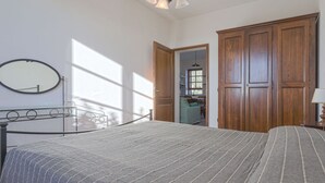 A bedroom with a bed, a wooden wardrobe, a mirror, and a view into the kitchen. - Beautiful apartment in villa with WIFI, A/C, pool, TV, patio, pets allowed and panoramic view (Castellina In Chianti)