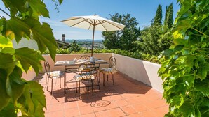 A patio with a table and chairs, an umbrella, and a view of the countryside. - Nice apartment in villa for 4 guests with WIFI, pool, TV, terrace and panoramic view (Colle Di Val D'elsa)