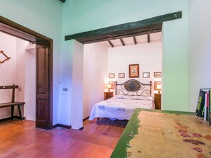 Une chambre à coucher avec un lit, un banc en bois, une porte et un mur orné de tableaux.