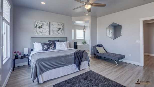A modern bedroom with a large bed, a ceiling fan, and artwork on the walls.