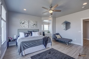 A modern bedroom with a large bed, a ceiling fan, and artwork on the walls.
