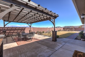 A covered patio with a table and chairs, a pergola, and a view of a mountain range.
