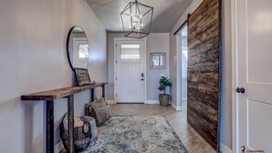 A hallway with a wooden bench, a mirror, a rug, and a door with a wooden panel. - Parking galore, quiet & bonus- electrical RV hookup! (Saint George)