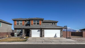 A two-story house with a garage, a front porch, and a mountain view.