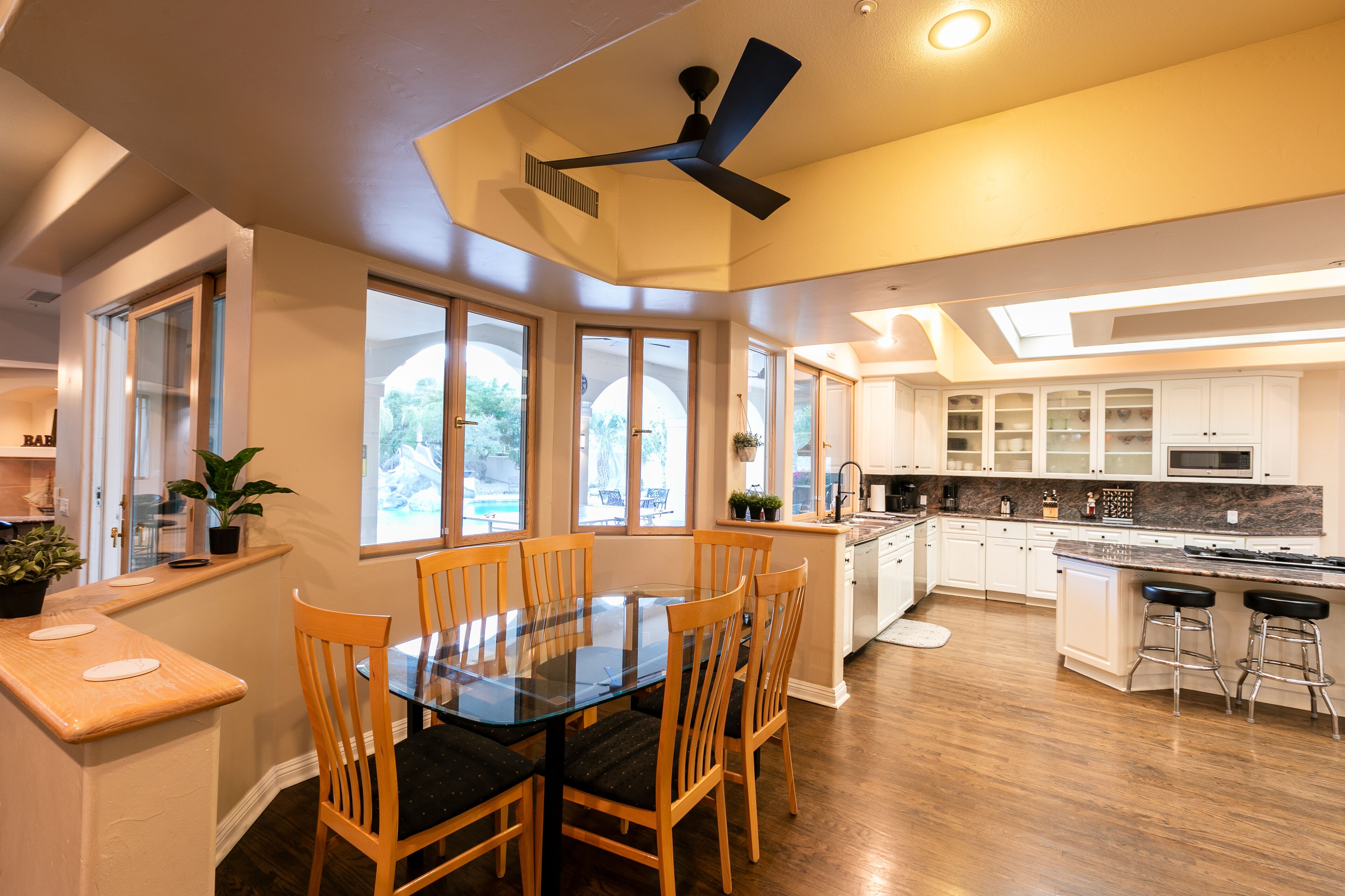 A modern kitchen with a central island, wooden chairs, and a dining table.