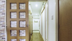 A hallway with a wooden door featuring frosted glass panels, a wooden floor, and white walls. - Nestle Tokyo Deluxe Akihabara 02 (Tokyo)