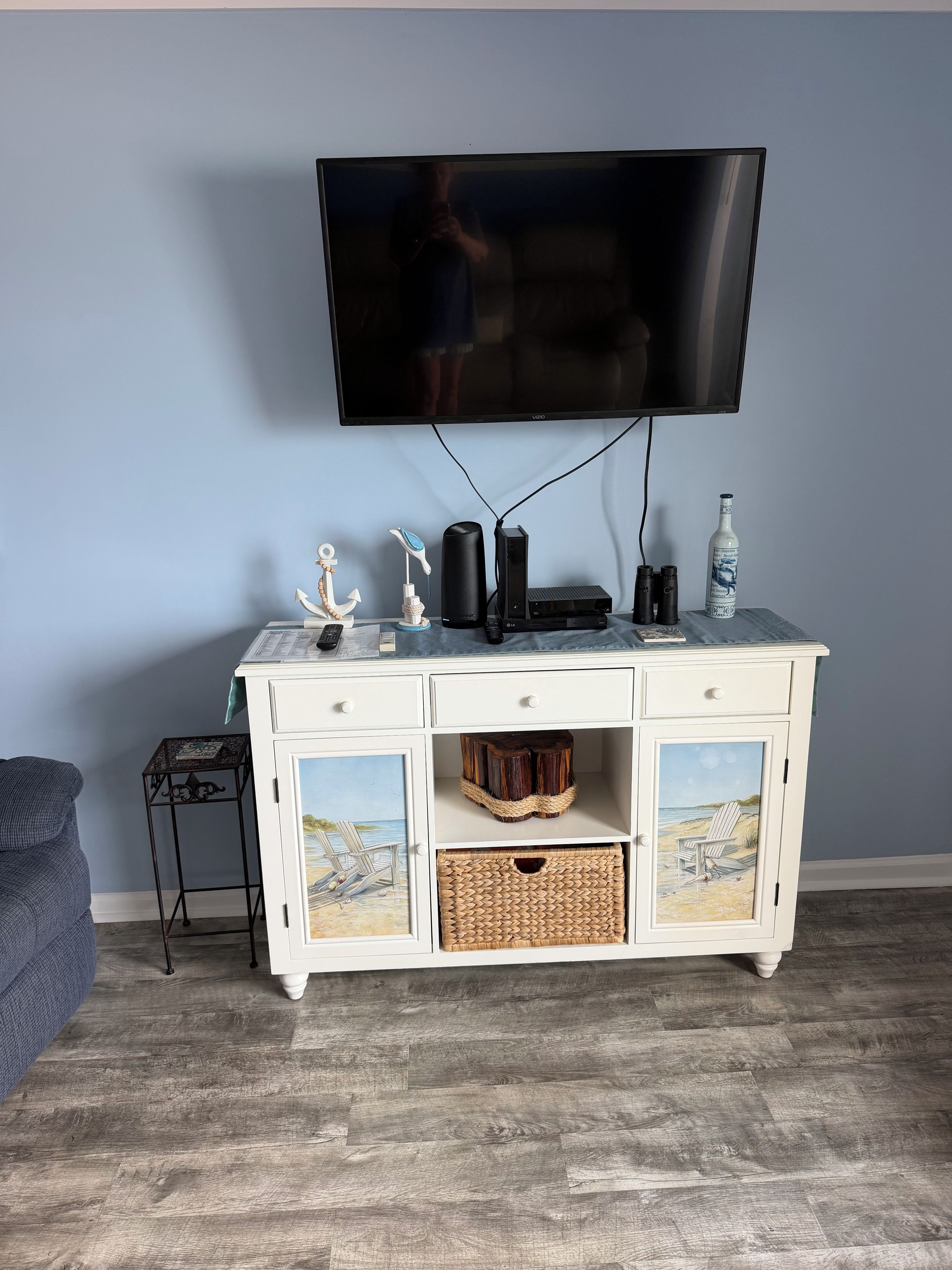 A room with a white entertainment center, a flat-screen TV mounted on the wall, and a grey sofa.