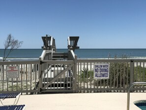 Una puerta de acceso a la playa con letreros que indican aguas poco profundas y prohibido bucear.