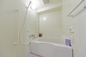 A small, white bathroom with a bathtub, a showerhead, and a towel rack.
