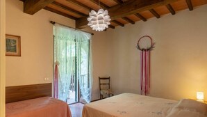A bedroom with two beds, a wooden ceiling, a window with sheer curtains, and a dreamcatcher on the wall. - Cosy apartment in villa for 4 people with WIFI, pool, TV, patio, pets allowed and panoramic view (Dicomano)